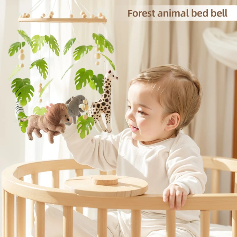 Wooden crib mobile with felt forest animals and green leaves, baby reaching.