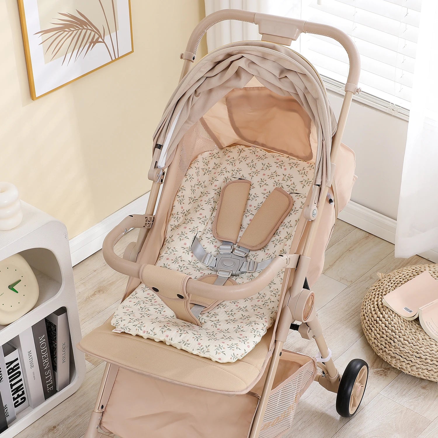 Beige baby stroller with a floral patterned cotton-polyester seat cushion and safety harness.