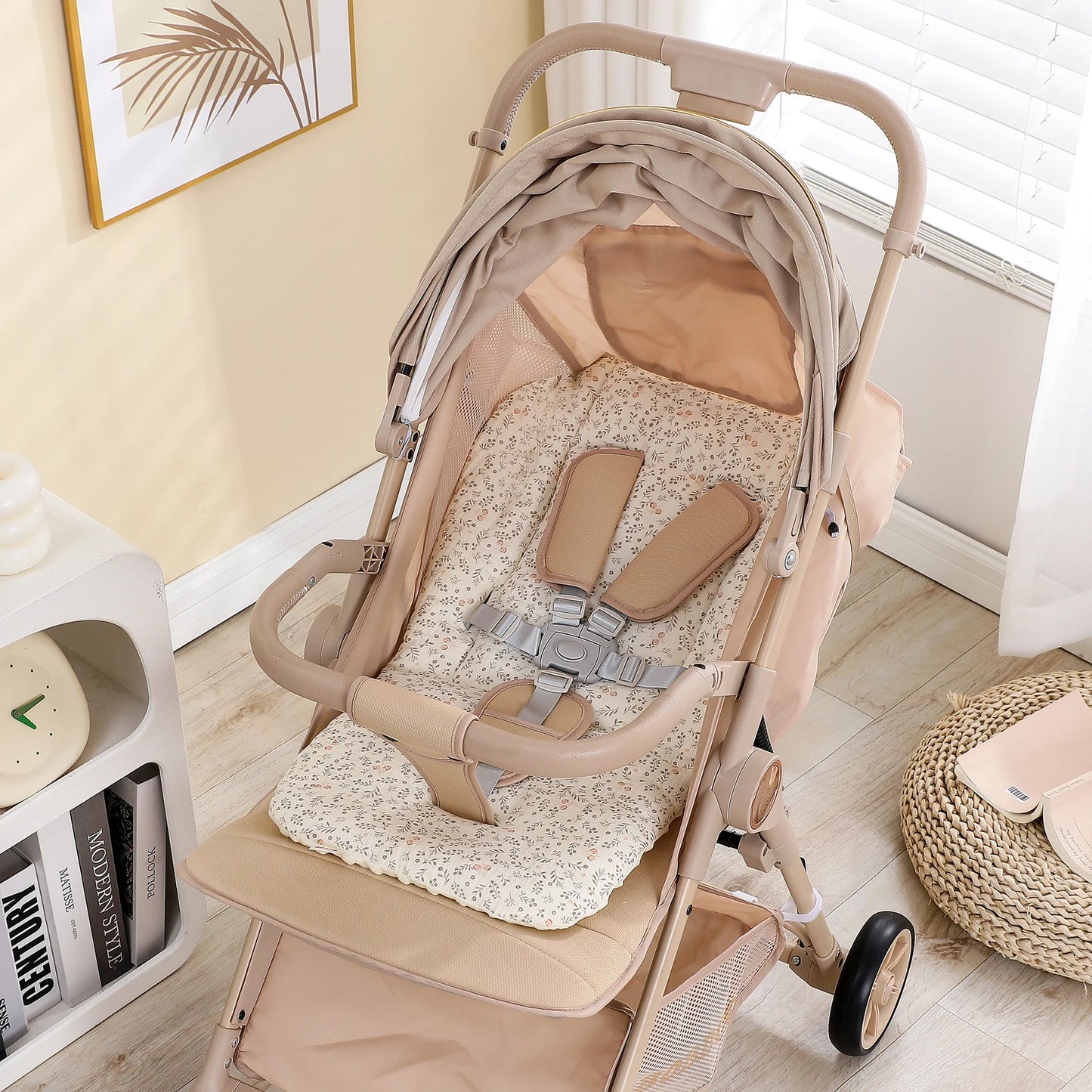 Beige baby stroller with a soft, floral-patterned cotton and polyester seat cushion and safety harness.