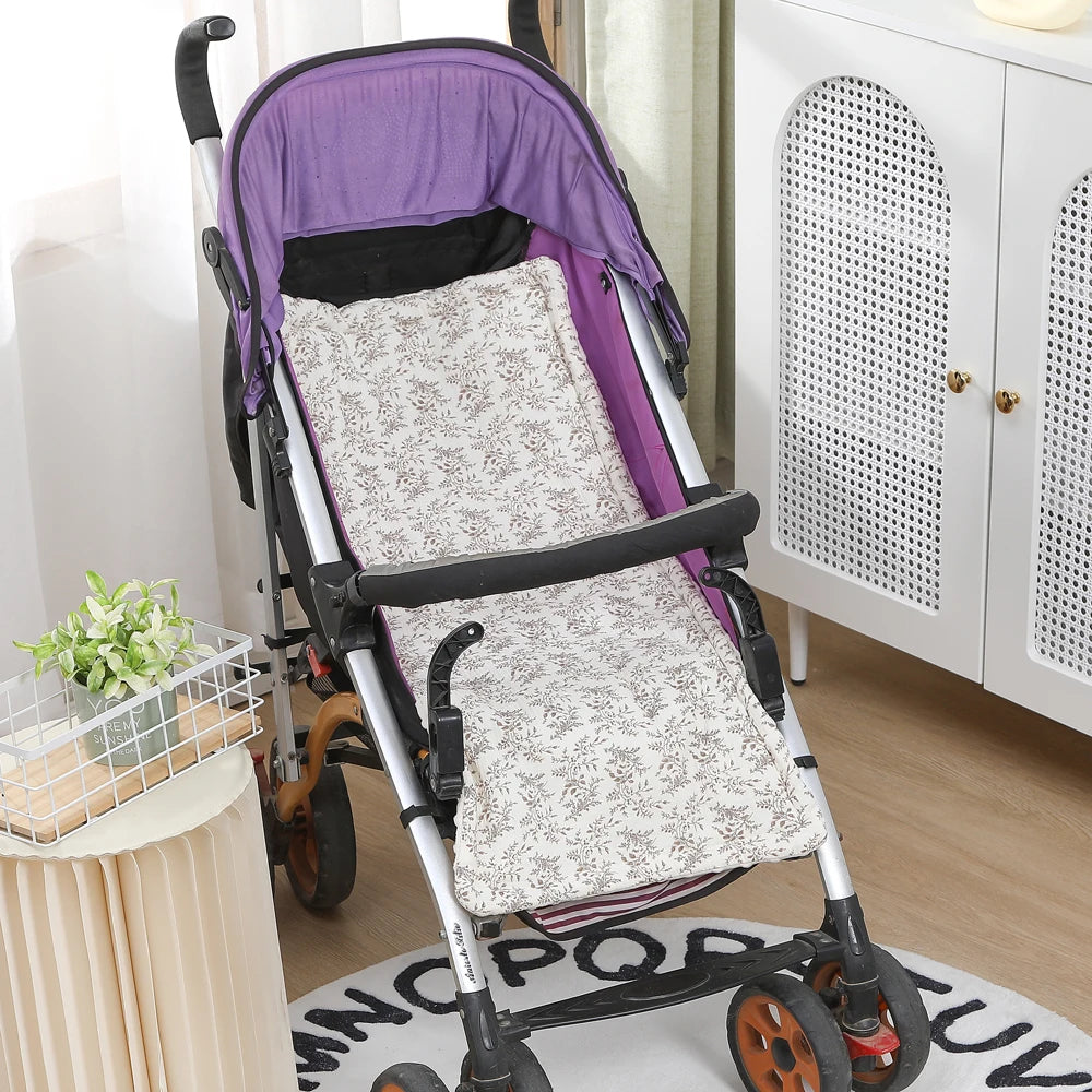 Soft, universal baby stroller cushion with a beige floral pattern, enhancing comfort in a purple stroller.