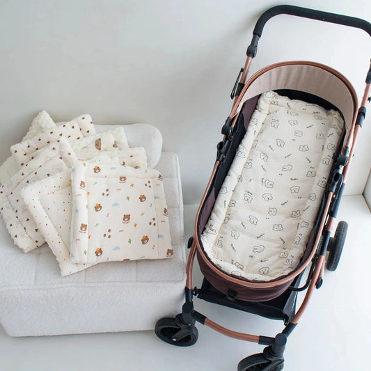 Soft beige stroller cushion with rabbit print inside a brown stroller, next to stacked cushions with bear and cloud patterns.