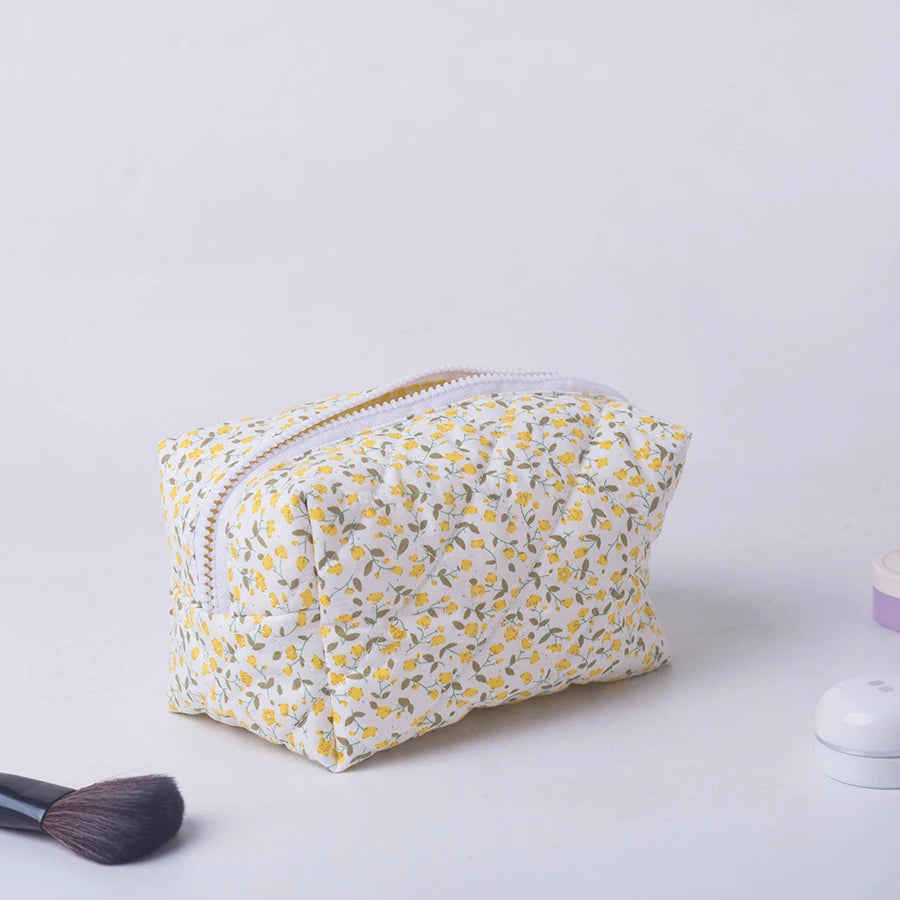Quilted white makeup bag with yellow floral print, white zipper, and soft texture.