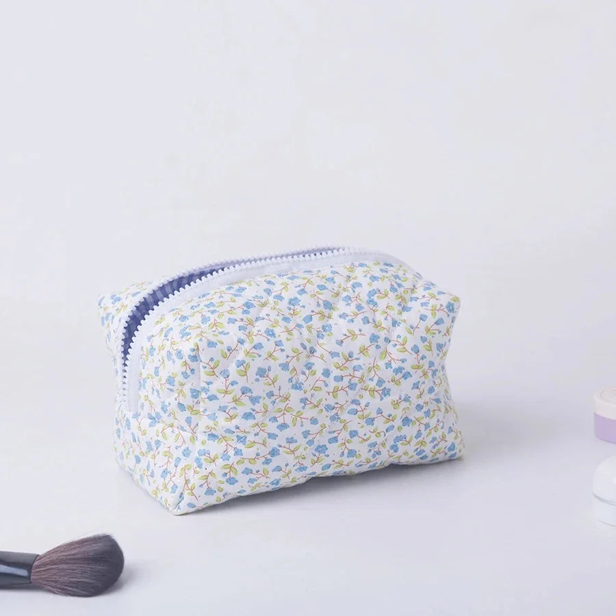 Padded floral makeup bag with blue flowers, white zipper, and soft polyester fabric.