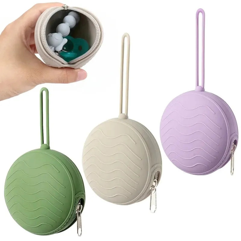 Three round silicone pacifier cases with zippers in green, beige, and lavender, one held open showing a pacifier.
