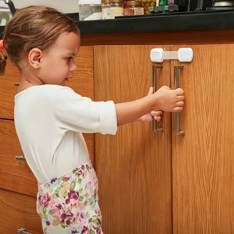 Child attempting to open a wooden cabinet secured with a white, drill-free safety lock.