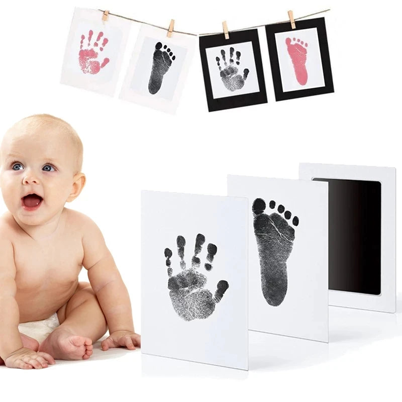 Baby hand and foot print kit with black ink pad, white cards, and a baby.