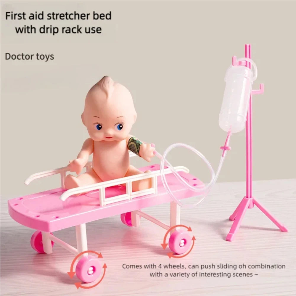 Pink toy stretcher bed with a baby doll and a pink IV drip stand.