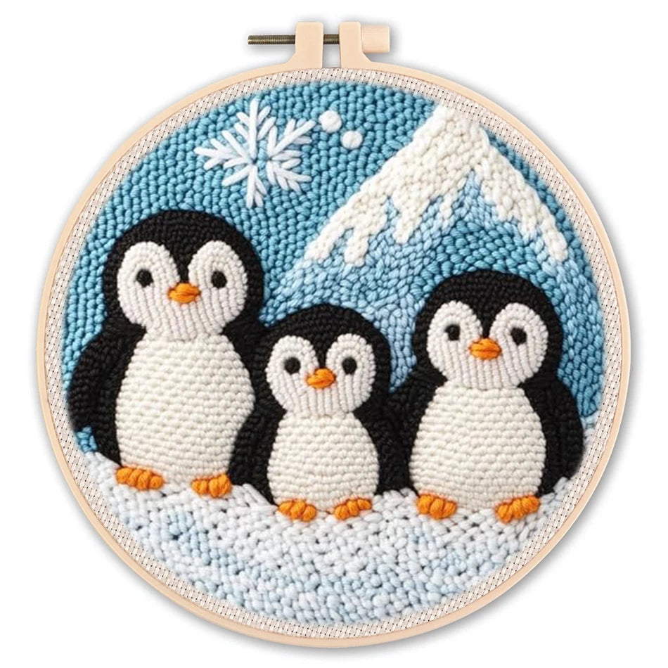 Punch needle embroidery kit featuring three cute penguins on a snowy mountain with a snowflake, in a round hoop.
