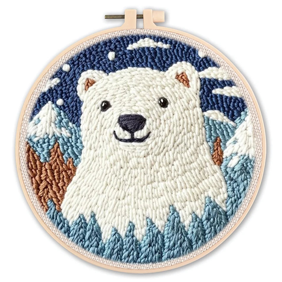 Punch needle embroidery kit featuring a cute polar bear in a snowy mountain scene, framed in a light wood hoop.