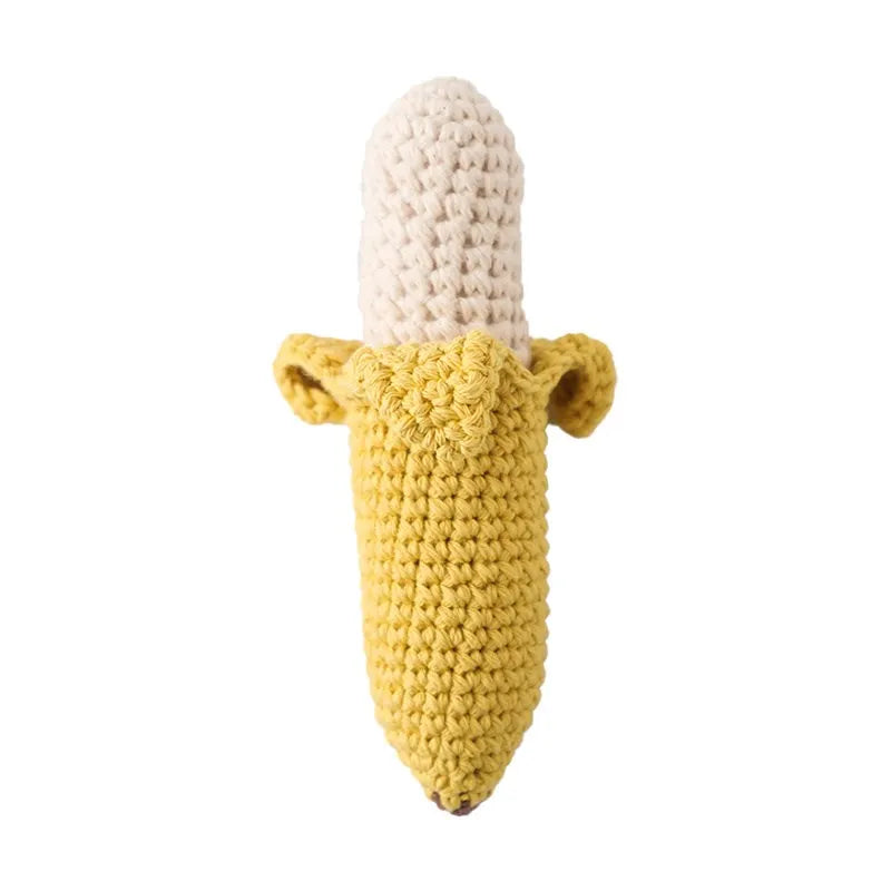 Crochet banana baby rattle with soft yellow peel and cream fruit, natural wood handle.