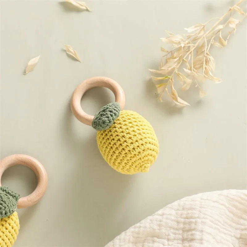 Crochet lemon fruit baby rattle with natural wood ring, yellow and green.