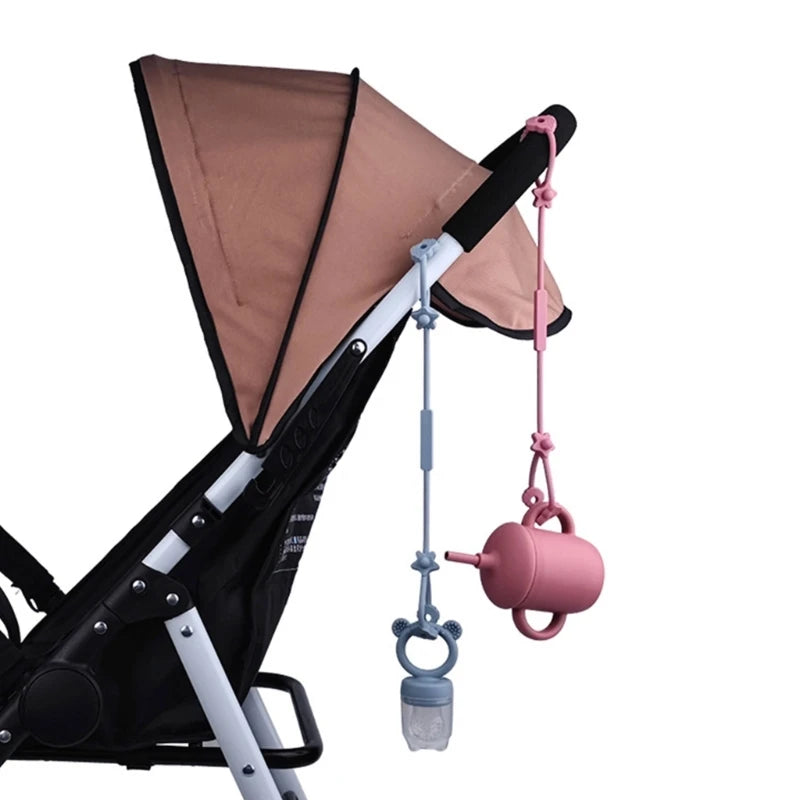 Adjustable pink and blue silicone pacifier and bottle straps attached to a baby stroller.