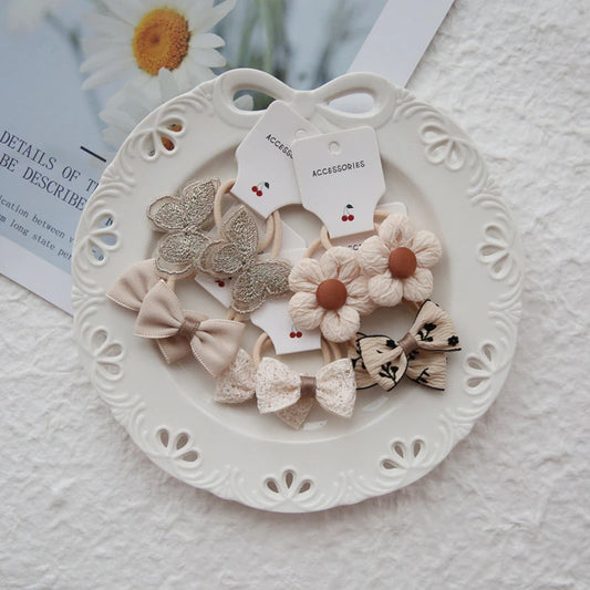 Set of 10 girls' hair ties with floral, butterfly, and bow designs in soft, neutral colors.