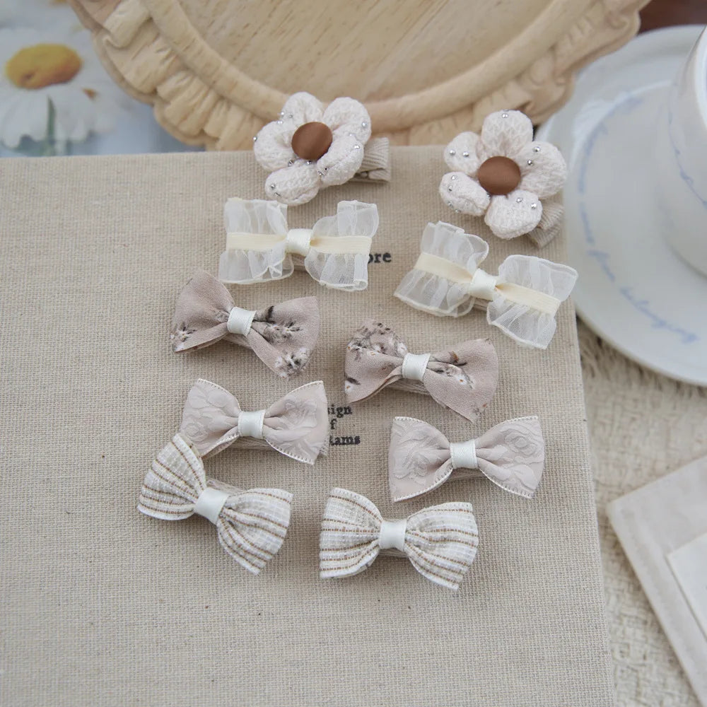 Set of 10 beige and white cotton hair clips for babies and girls, featuring bows and flower designs.
