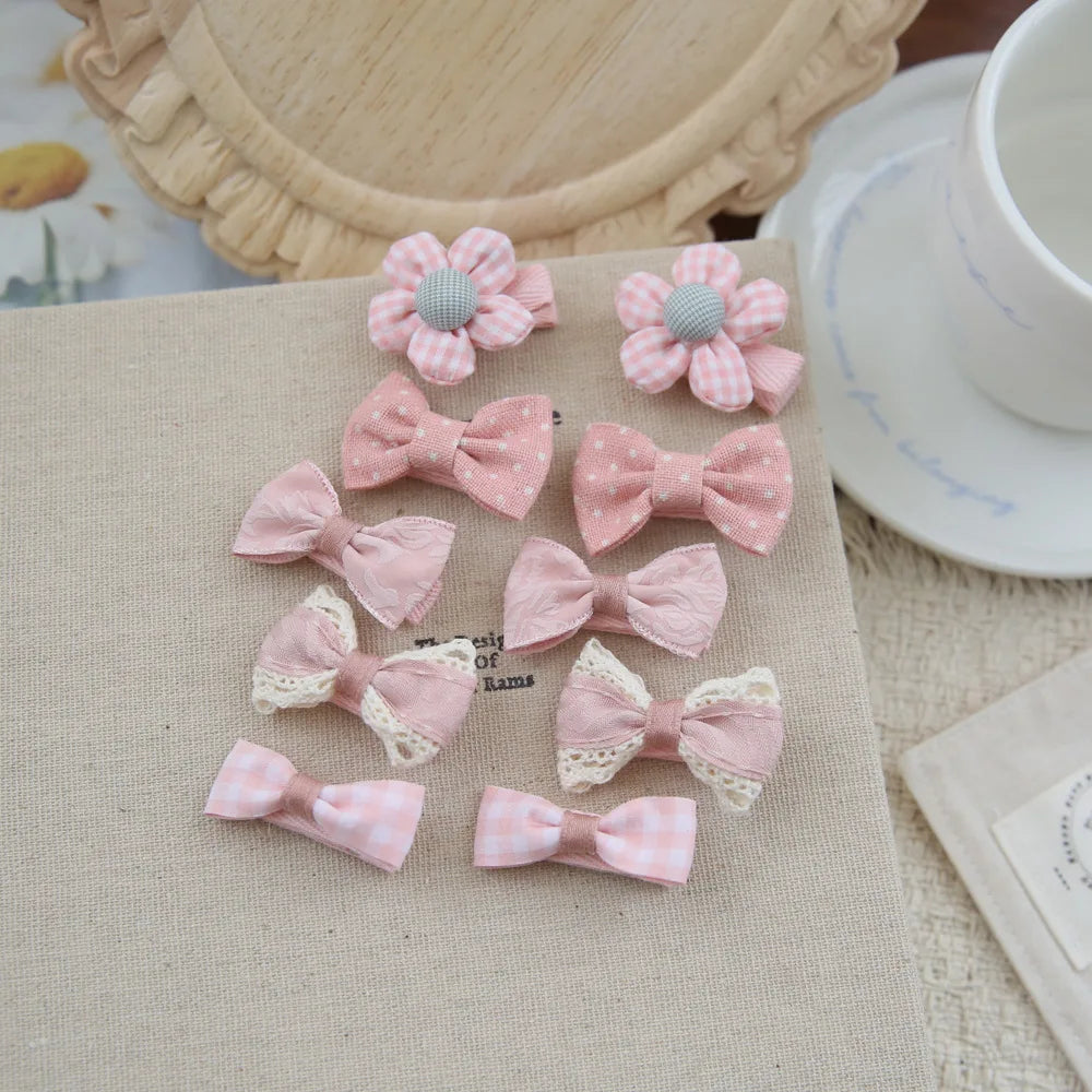 Set of 10 pink fabric hair clips for babies and girls, featuring bows and flowers with soft textures.
