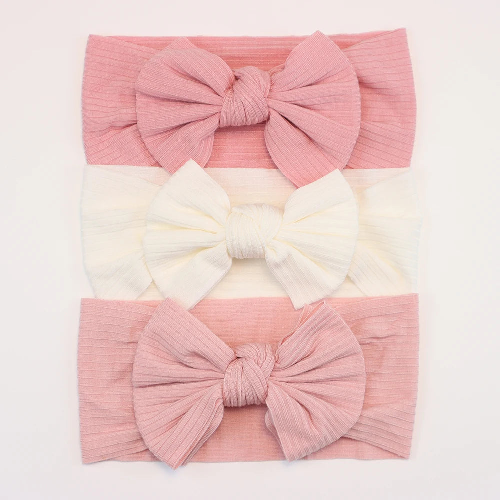 Set of 3 soft, flexible nylon baby headbands with bows in pink and cream, for ages 0-3.