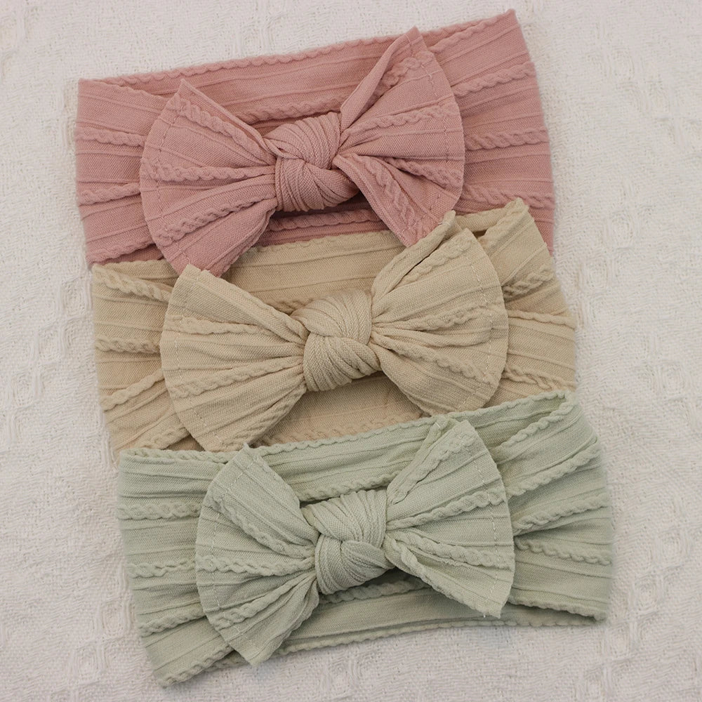 Set of 3 soft nylon baby headbands with bows in pink, beige, and mint green.