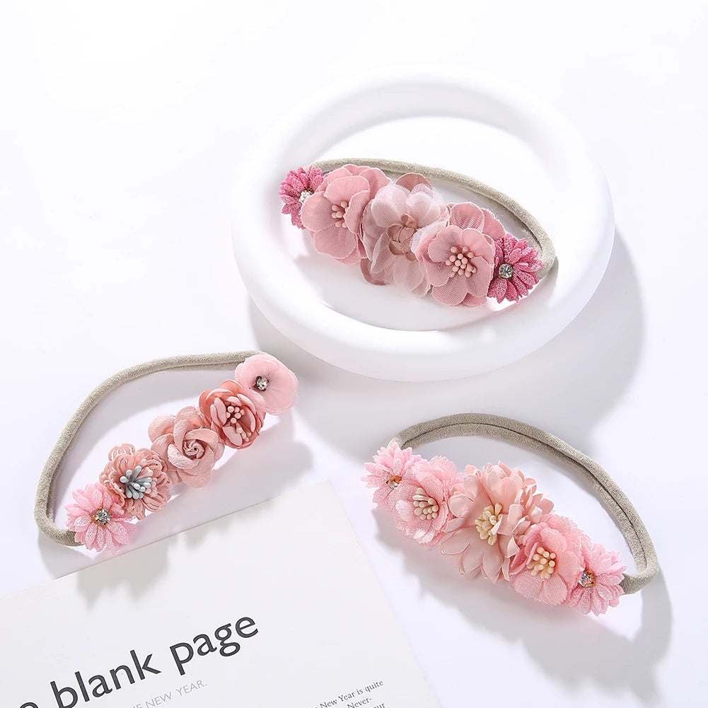 Set of 3 soft nylon baby headbands with pink floral designs and elastic bands.