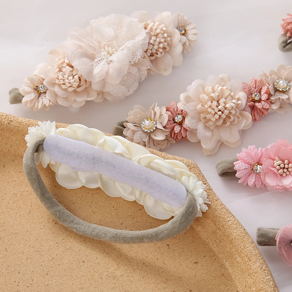 Set of 3 soft nylon baby headbands with delicate pink and beige floral designs, pearls, and rhinestones.