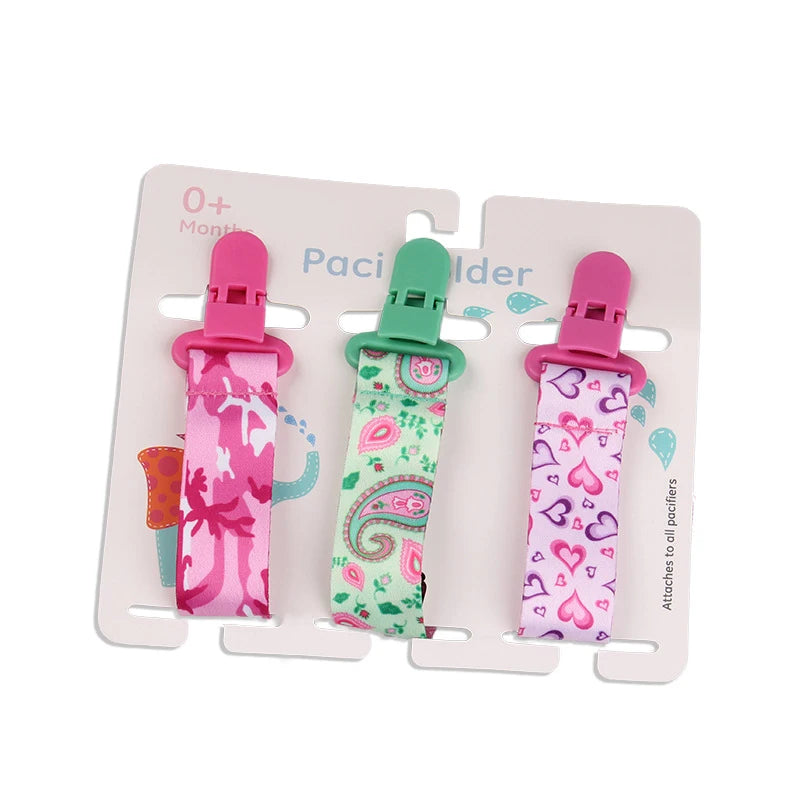 Set of 3 polyester pacifier clips with pink and green plastic clasps, featuring camouflage, paisley, and heart patterns.