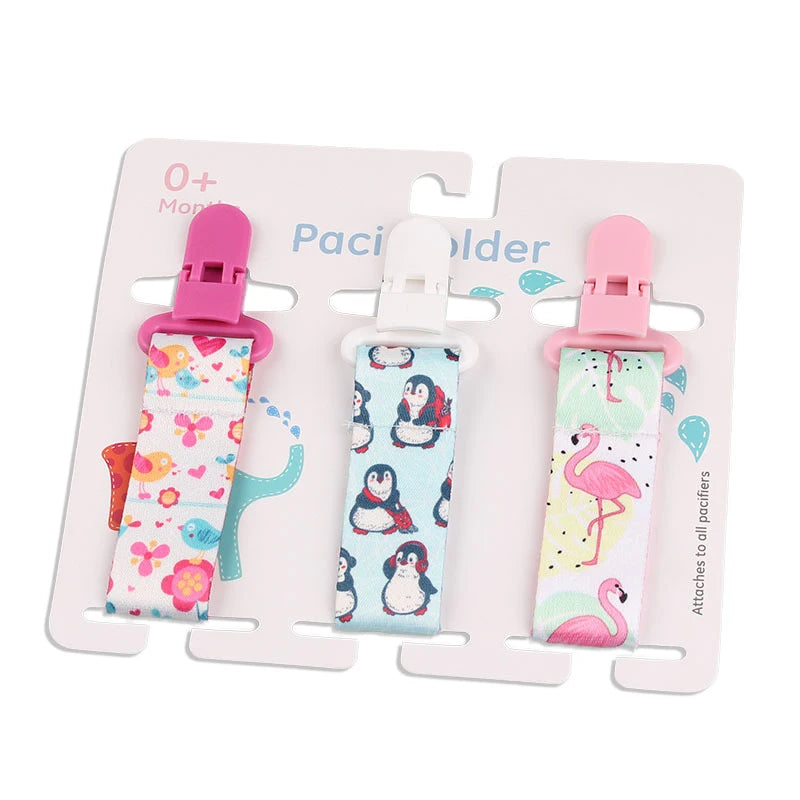Set of 3 baby pacifier clips with colorful fabric straps featuring birds, penguins, and flamingos, and plastic clasps.