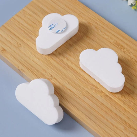 Set of 3 white cloud-shaped silicone door stoppers with adhesive backing on a wooden surface.