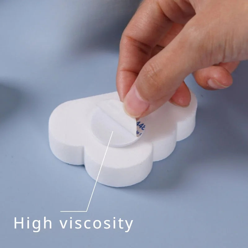 Hand applying a white, cloud-shaped silicone door stopper with strong adhesive backing.