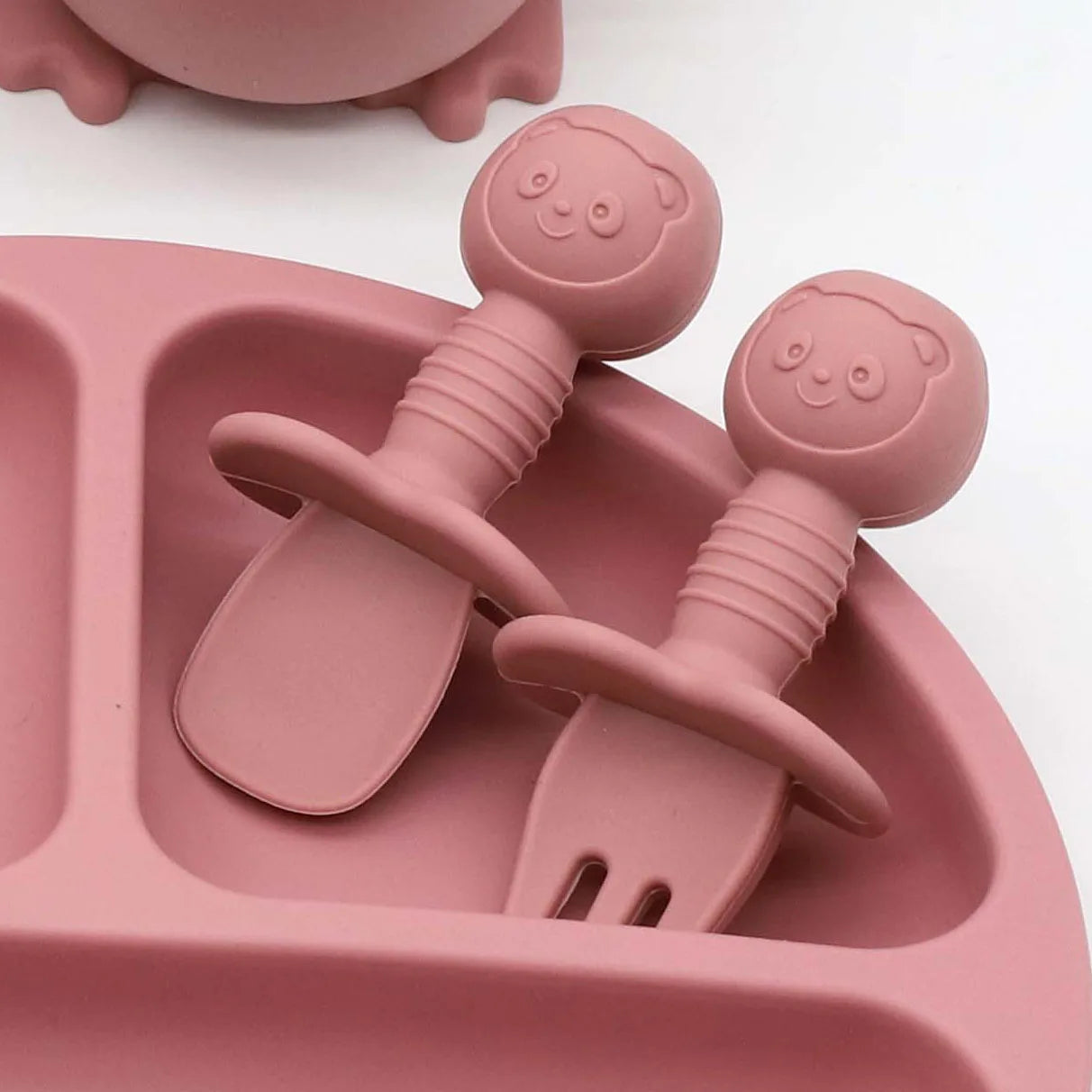Pink silicone baby feeding set with divided plate, spoon, and fork with panda handles.