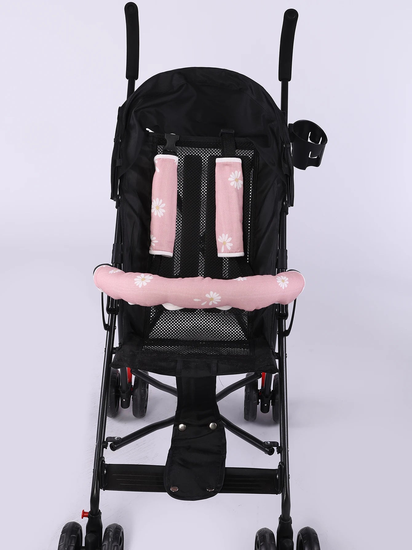 Pink daisy-patterned stroller handle cover and matching safety belt pads on a black stroller.