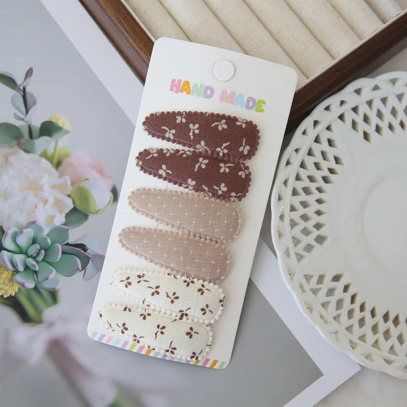 Set of 6 handmade floral snap hair clips for girls in brown, beige, and cream cotton.