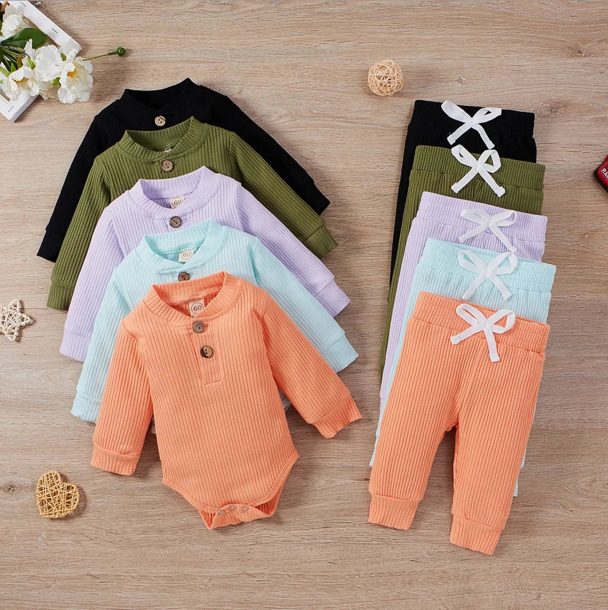 Ribbed cotton long-sleeve baby bodysuits and pants in black, olive, lavender, blue, and peach.