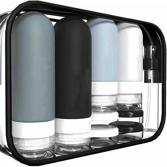 Travel toiletry set with four refillable silicone bottles in grey, black, light blue, and white, plus clear jars and a spray bottle, all in a transparent zippered pouch.