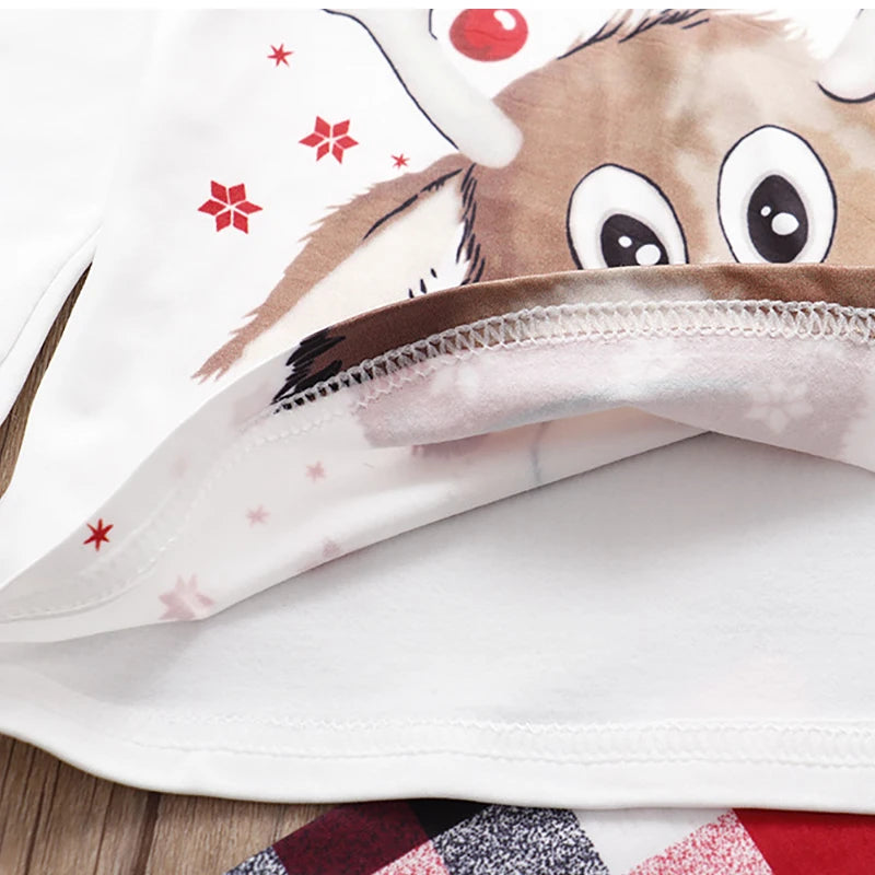 Close-up of a white polyester Christmas pajama top with a reindeer print and red snowflakes.
