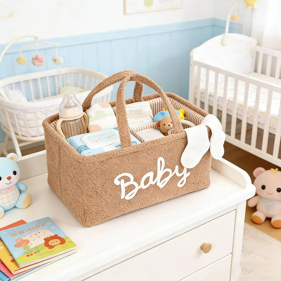 Brown fleece baby diaper caddy with "Baby" text, handles, and compartments, filled with essentials on a changing table.