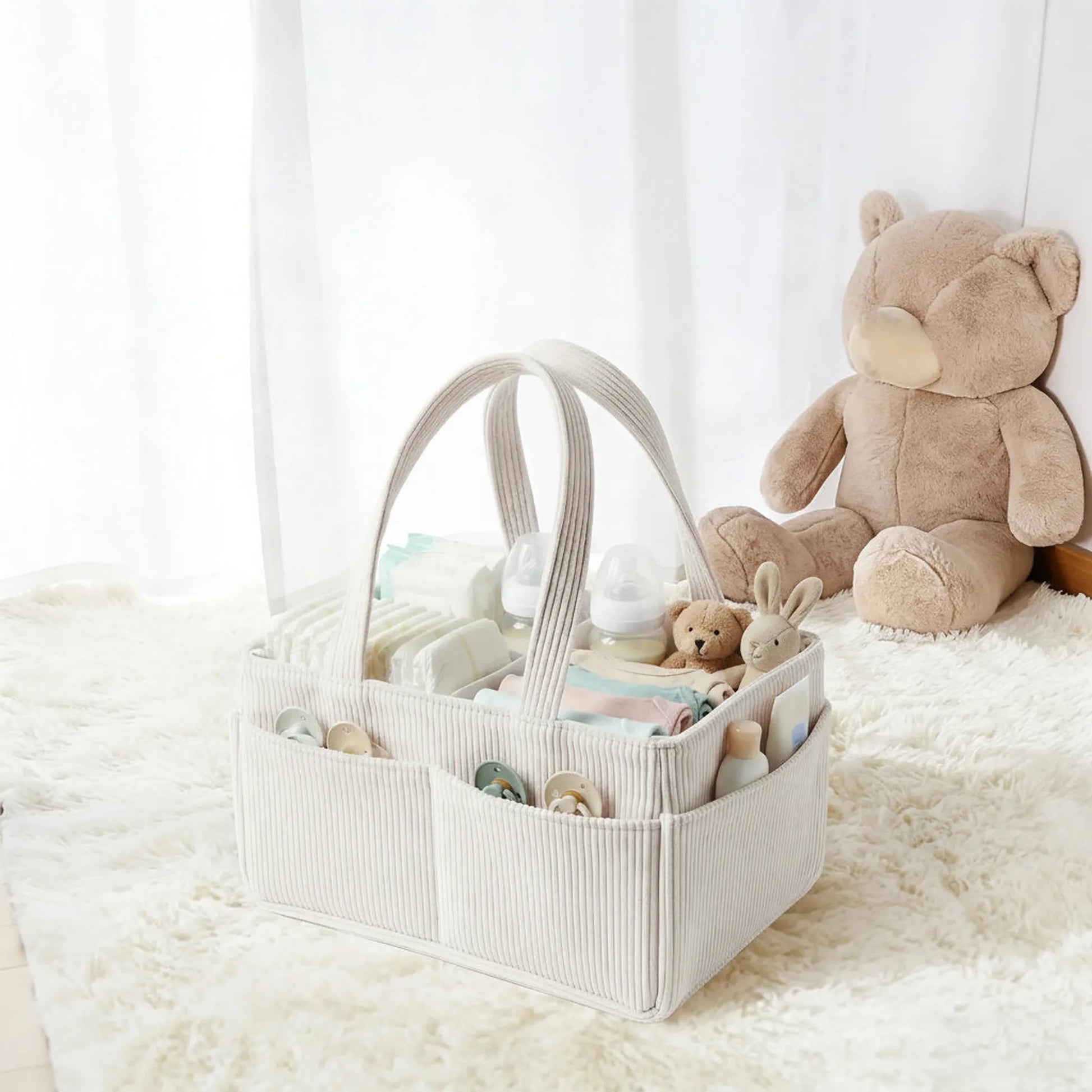 Beige corduroy and felt diaper caddy with handles, filled with baby essentials, on a white rug.