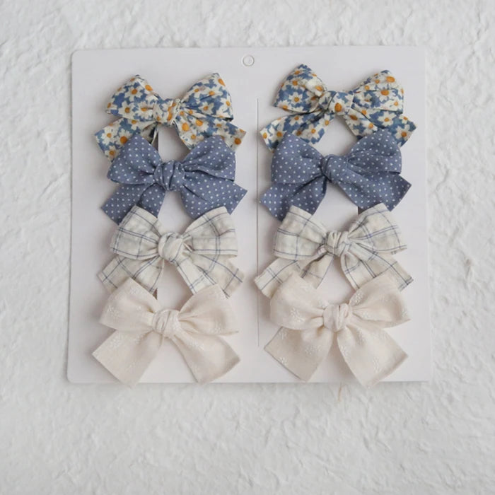 Set of 8 girls' cotton hair clips with elegant bows in floral, polka dot, plaid, and solid cream designs.
