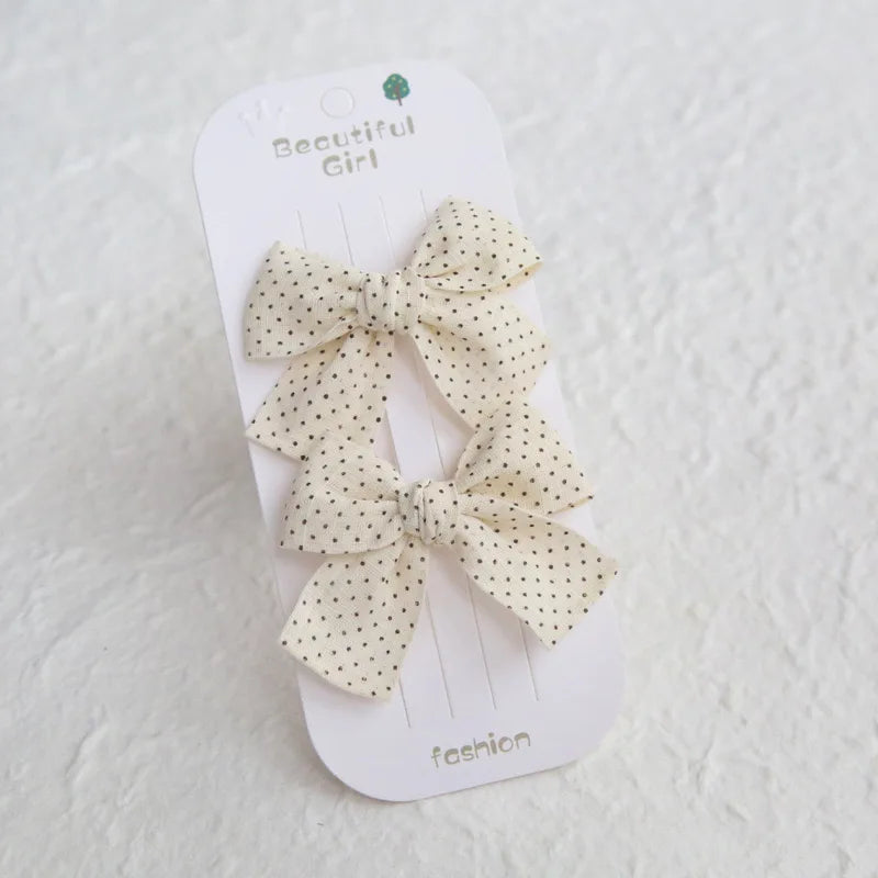 Two cream cotton hair bows with black polka dots on a "Beautiful Girl" card.