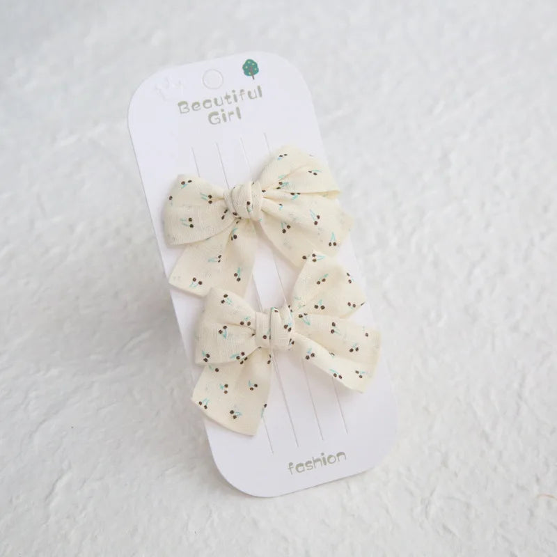 Two cream cotton hair bows with small cherry print on a "Beautiful Girl" card.