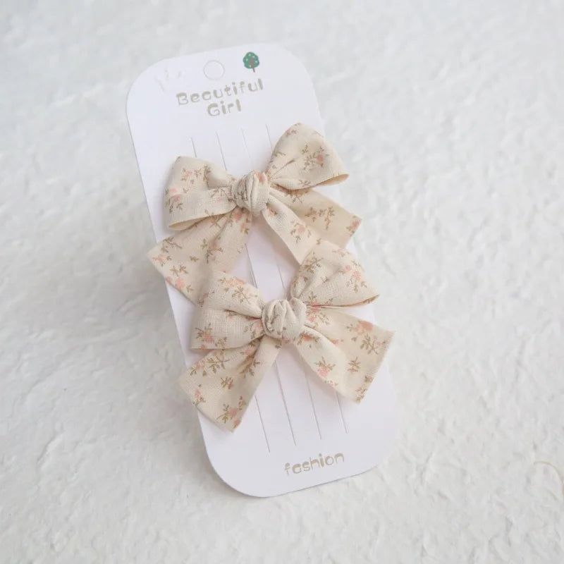 Two beige cotton hair bows with pink floral print on a "Beautiful Girl" card.