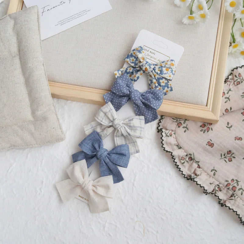 Set of five elegant cotton hair bows for girls in blue, white, and floral patterns.