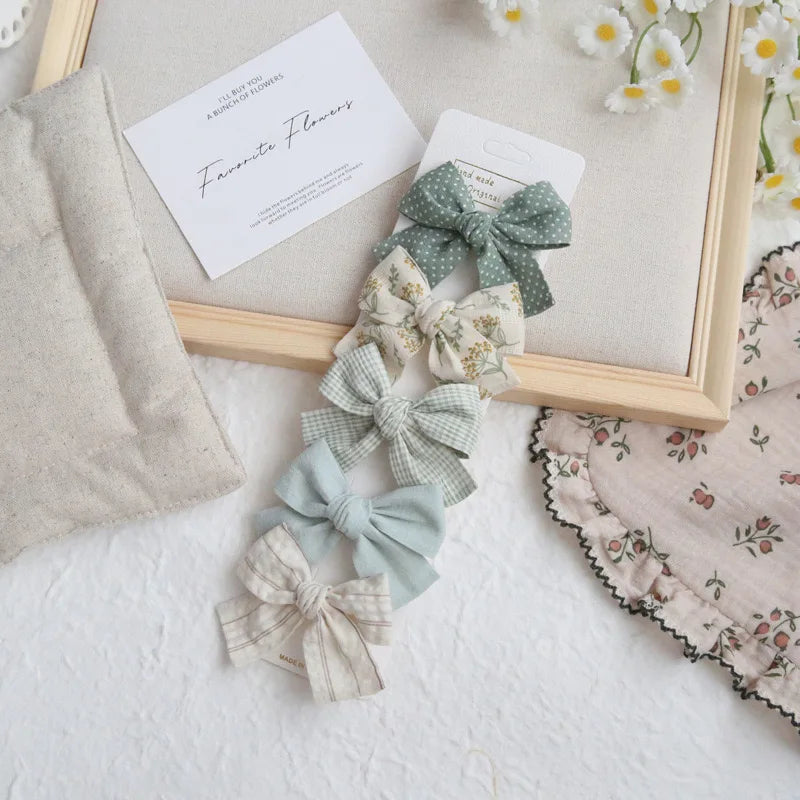 Set of five cotton hair bows for girls in green, cream, and light blue, with various patterns.