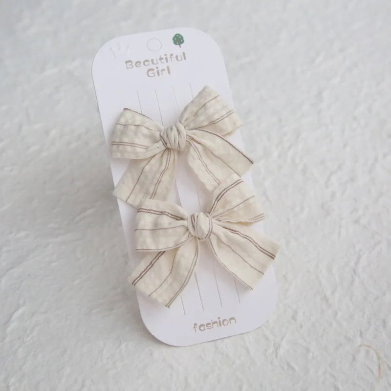 Two beige cotton hair bows with thin stripes on a "Beautiful Girl" card.