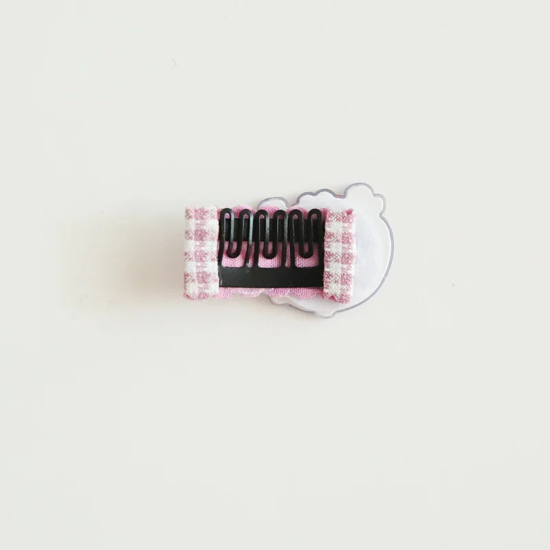 Back view of a pink gingham fabric baby hair clip with a decorative bow and secure black metal clip.