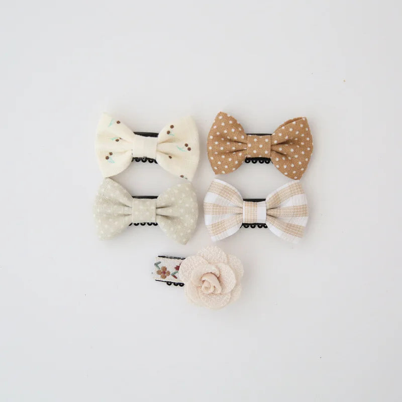 Set of five cute baby hair clips: two polka dot, one floral, one striped bow, and one cream rose.