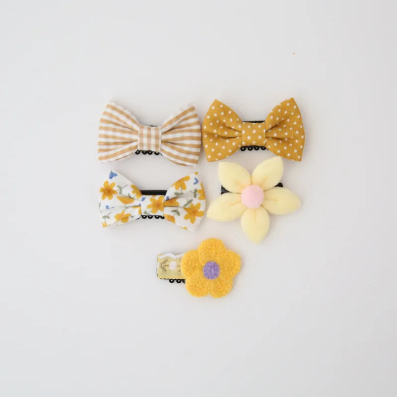Set of five cute baby hair clips: two yellow bow clips (striped, polka dot), two floral bow clips, and one yellow flower clip.