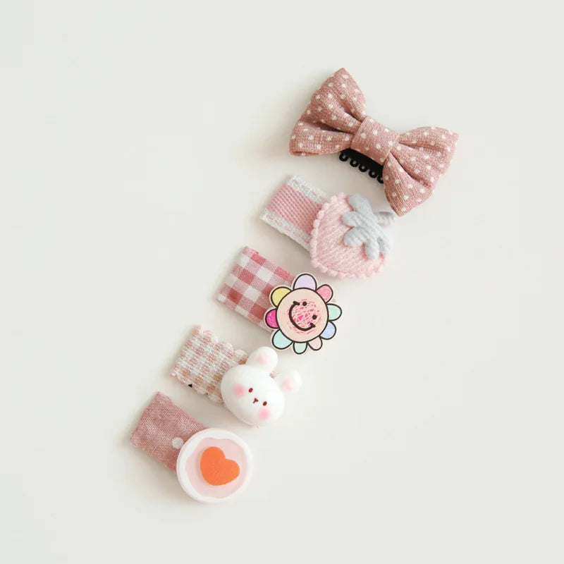 Set of five pink and white cotton baby hair clips with decorative bows, a bunny, and a flower.