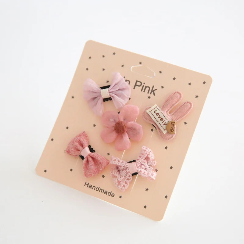 Set of five pink cotton baby hair clips: two bows, a flower, a lace bow, and a bunny clip.