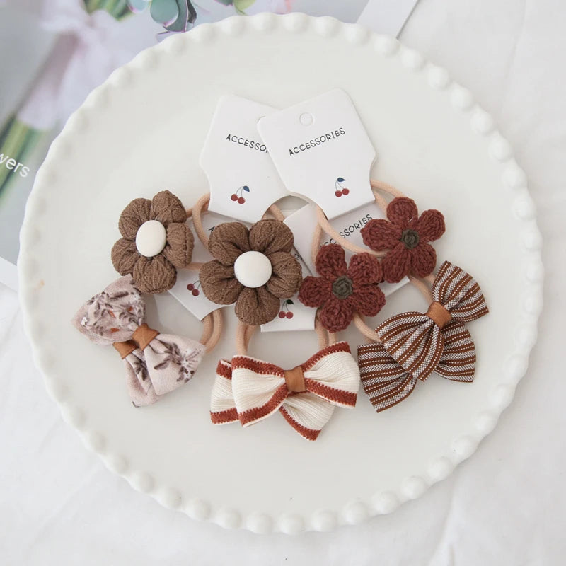 Handmade cotton floral and bow hair ties for girls in brown, cream, and striped designs.
