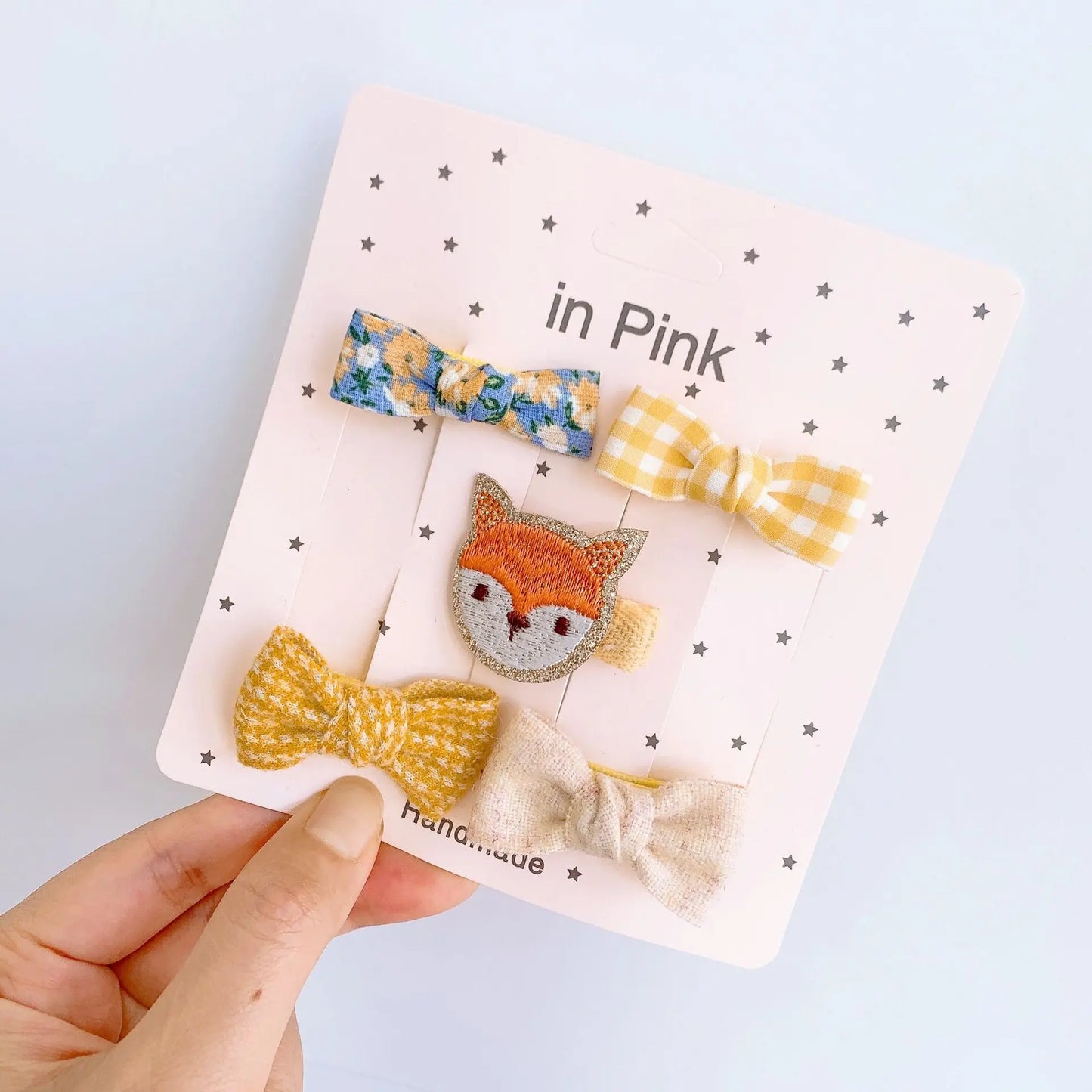 Set of 5 baby girl hair clips: floral blue, yellow gingham, embroidered fox, textured yellow, and beige bows.
