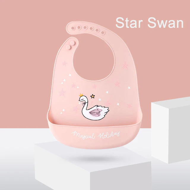 Pink silicone baby bib with a swan and star design, adjustable neck, and food-catching pocket.